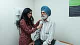 A female doctor uses a stethoscope to examine a senior man in a medical clinic.