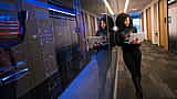 A professional holds a laptop next to glass-enclosed server racks in a modern data center.
