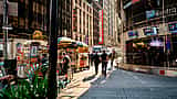Pedestrians and street vendors pass by the Nasdaq MarketSite building in Times Square, New York City.