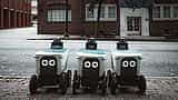 Autonomous delivery robots line up on an urban street, representing the use of artificial intelligence in modern retail and logistics.