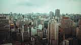 A dense urban skyline with modern high-rises and busy elevated highways in São Paulo, Brazil.