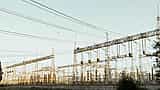 A complex electrical substation with numerous metal towers and power lines against a clear sky.