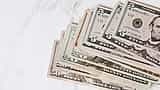 A stack of United States dollar bills rests on a marble surface.