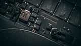 A close-up view of microchips and electronic components on a dark computer circuit board.