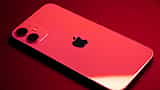 An iPhone bathed in deep red light, displaying the Apple logo on its back.