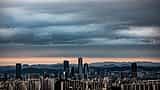 Heavy, dark clouds loom over the modern city skyline of Seoul.