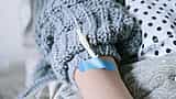 A close-up of a patient wearing a knitted sweater receiving an intravenous drip.