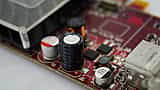 A close-up macro view of a black cylindrical capacitor and other electronic components mounted on a red computer circuit board.