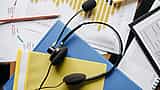 A customer service headset resting on colorful folders and printed financial charts.