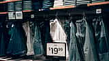 A retail display of denim jeans featuring clear price tags and discount signs.