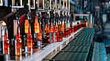 Glowing hot glass bottles move along an automated production line in a manufacturing plant.