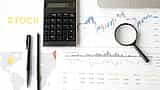 A flat lay of a desk featuring financial line charts, a dotted world map graphic, a calculator, and a magnifying glass.
