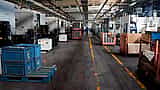 A wide view of a quiet, orderly factory floor lined with heavy machinery and crates of parts.
