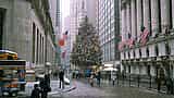 A large decorated Christmas tree stands outside the New York Stock Exchange building during a winter snowfall.