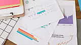 Printed financial documents and charts scattered on a desk, including a graph tracking the S&P 500 index.