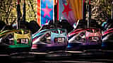 Three brightly colored bumper cars with thick rubber rims lined up side-by-side.