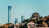 Traditional Chinese architecture in the foreground contrasts with the modern skyscrapers of Beijing's central business district rising against a clear blue sky.