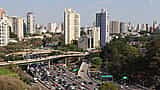 An aerial view of the urban skyline and a bustling expressway in São Paulo, Brazil.