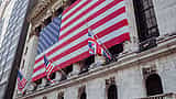 A giant American flag hangs across the classical facade of the New York Stock Exchange.