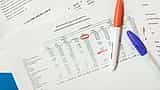 A printed financial statement detailing functional expenses lies on a desk alongside a red marker and a blue pen.