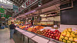 A bustling fruit stall in a Spanish market displaying fresh apples and pears with clear price tags.