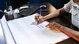 A professional writes notes on a large desk calendar in an office setting.