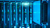 A metal server blade partially slid out of a glowing blue data center rack.