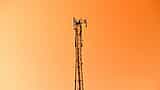 A telecommunications tower stands against a vibrant orange sky.