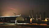 Silhouetted Starship rockets stand at the SpaceX Starbase facility under a foggy night sky.