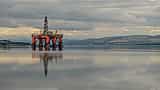 An offshore oil platform sits on a calm body of water beneath a dense, stormy sky.