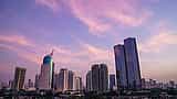 Modern skyscrapers rise into a pink and purple sunset sky in Jakarta, Indonesia.