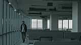 A single employee walks past rows of empty desks in a dimly lit office space.
