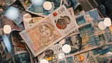 A close-up view of British five and ten pound sterling notes with a warm bokeh effect.