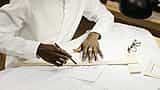 Close-up of a professional's hands using a pencil and ruler to draft architectural blueprints.