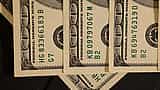 A close-up view of U.S. dollar bills highlighting the Federal Reserve seal and serial numbers.