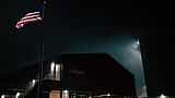A large American flag is displayed on the side of the Stargate building at night.