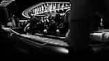 Black and white photograph of people placing bets around a casino craps table.