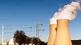 Cooling towers and high-voltage transmission lines of a power plant against a clear blue sky.
