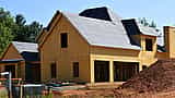 A wooden residential house with exposed framing and sheathing under construction.