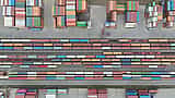 An aerial view of colorful shipping containers arranged in stacks of varying sizes at a storage terminal.