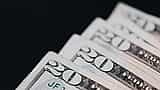 A macro shot of United States twenty-dollar bills neatly layered against a stark black background.