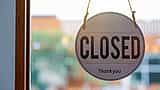 A round wooden closed sign hanging on the inside of a glass window or door.