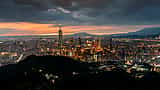 A sweeping view of the modern Taipei skyline at sunset, anchored by the towering Taipei 101 skyscraper.