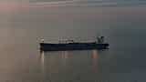A large oil tanker sails alone across a vast, dim ocean at twilight.