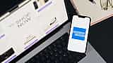 The American Express logo is displayed on a smartphone screen resting on a laptop keyboard.