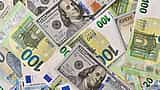 U.S. hundred-dollar bills and hundred-euro banknotes lie overlapping on a flat surface.