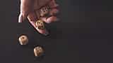 A hand rolling three wooden dice onto a dark surface in moody, dramatic lighting.