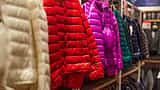 Brightly colored winter jackets hang on a clothing rack in a retail store.