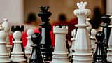 A close-up view of black and white chess pieces clustered together on a chessboard.