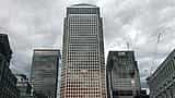 The Citi and HSBC logos top neighboring skyscrapers in London's Canary Wharf under a cloudy sky.